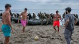 Pictured: Royal Marines conduct drills for D-Day reenactment while beachgoers play football
