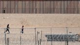 Video shows migrants rush border wall, try to climb over