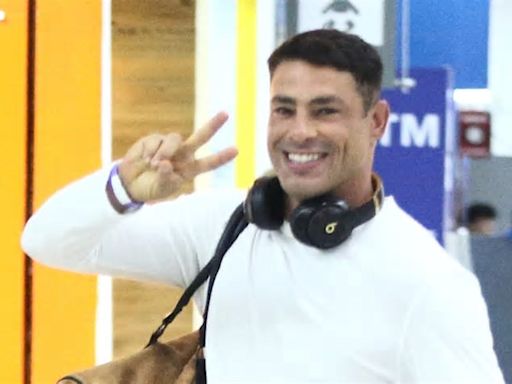 Cauã Reymond posa sorridente após desembarcar em aeroporto do Rio