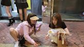 網上熱話｜兩女踎過路處享用香港街頭小食 網民：唔腳痹先勁