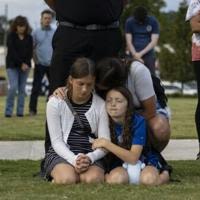 A mother and her children bow their heads in prayer at a vigil for the victims of the Apalachee High School shooting in Winder, Georgia