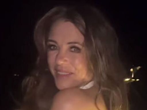 Braless Liz Hurley, 58, almost flashes fans as she dances in risqué white dress