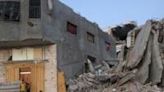 Palestinians sit by a damaged building surrounded by rubble at al-Bureij camp in the central Gaza Strip on Sunday