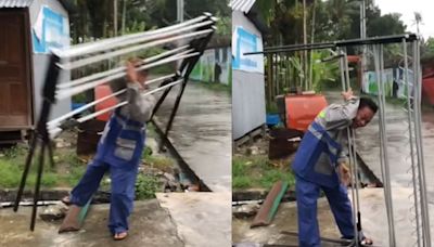 Man Struggles To Carry 3V Hanger On Rainy Road, Friend Laughs Uncontrollably & Records Video Instead Of Helping Him