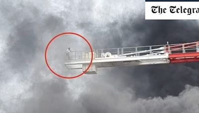 Watch: Man teeters on edge of crane during London tower block fire