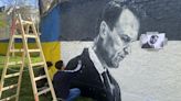 Artists spray-paint portraits of Alexei Navalny behind a Soviet monument in Vienna