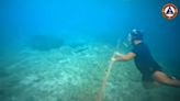 Un buzo filipino ayuda a eliminar con un cuchillo una barrera flotante instalada por China en el mar de China Meridional