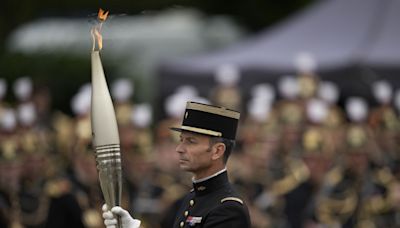 The Olympic torch lights up France's Bastille Day military parade