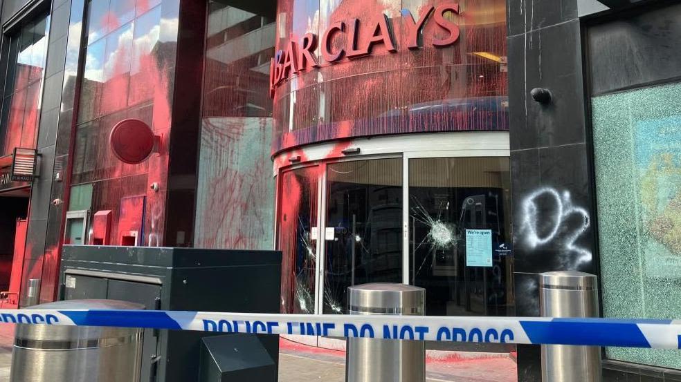 Seven deny criminal damage over bank paint attack
