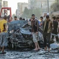 Palestinians check a burnt vehicle following an Israeli strike in the central Gaza Strip