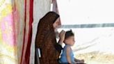 A Palestinian woman sits with a child at a camp for displaced people in Deir al-Balah, in the central Gaza Strip