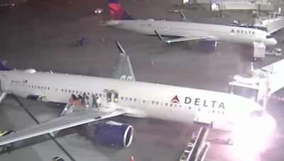 Passengers flee down emergency slides as Delta plane catches fire on airport tarmac