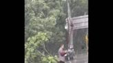 China: Selfless Man Lifts Downed Wire With Spade For Passing Cars In Rain