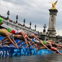 Triathletes dive into the River Seine at the start of the Olympic triathlon