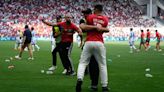 Fans invade pitch and throw objects at players after Argentina net 116th-minute equaliser in Olympic opener