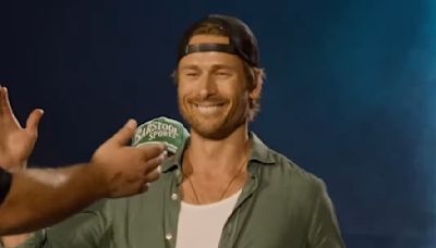 Glen Powell chugs a beer on stage at Luke Combs concert