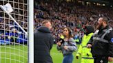 Fan confronts stewards armed with corner flag as fans invade pitch after key win