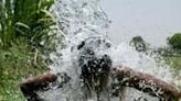 A man takes a shower under water pouring from a pipe along the Yamuna flood plains on a hot summer afternoon in New Delhi on May 29