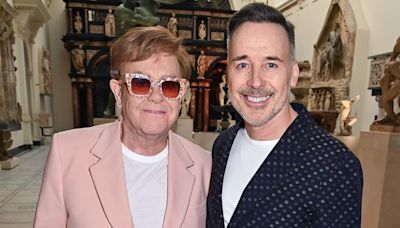 Elton John is supported by husband David Furnish at V&A exhibition