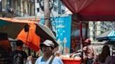 A woman walks with a cold drink down a street in Yangon, where extreme heat has played havoc recently