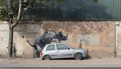 Banksy unveils rhino artwork that looks like the animal is climbing onto a car