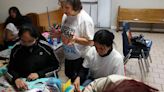 Doris Hernandez, standing, and community activist Dolores Castaneda, seated to the right of her, help children make Mother’ s Day cards at the Prince of Peace Eucharistic Adoration Chapel at St...