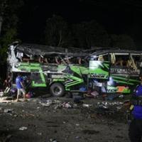 Officers check the debris and belongings of passengers after a bus crash on Java island