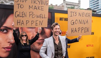Glen Powell’s Parents Showed Up on His Red Carpet With Signs Trolling Him: ‘Stop Trying to Make Glen Powell Happen’ and ‘It’s...