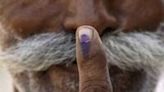 A voter displays his ink marked finger after casting his ballot at a polling station on May 7