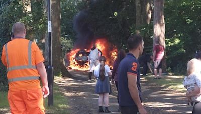 Firefighters tackle huge car fire on footpath as neighbours watch on