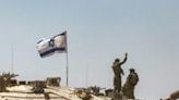 An Israeli army soldier gestures atop the turret of a main battle tank in southern Israel near the Gaza border