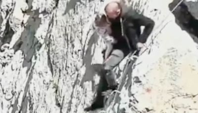 Shocking moment tourist carries his baby along narrow mountain ledge