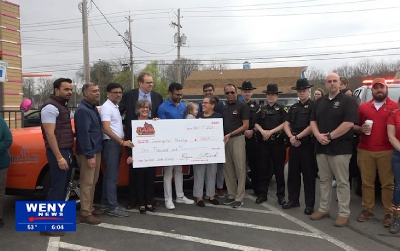 Dunkin' in Elmira presents check for Investigator Theetge and family