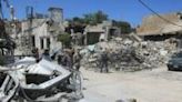 People walk past the rubble of a building that was destroyed by previous Israeli bombardment in the village of Yaroun in south Lebanon