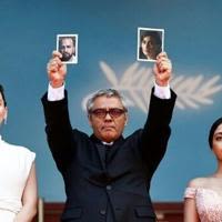 Mohammad Rasoulof of Iran held pictures of his actors on the red carpet