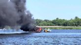 Black smoke billows from burning boat stuck in mud on Mass. river