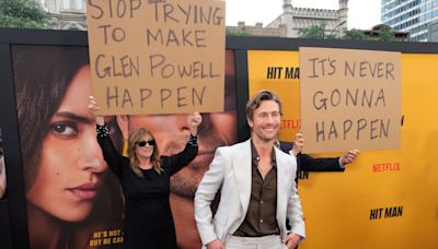 Glen Powell’s parents hilariously troll him with signs on Hit Man red carpet