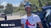 Djokovic greets fans with a helmet after being hit by bottle