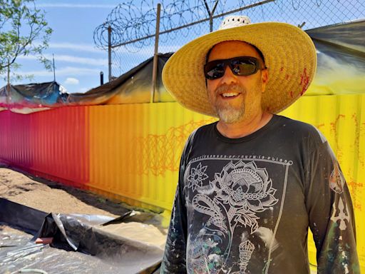 An artist is using sprinklers to paint the walls of a Spring Garden apartment complex