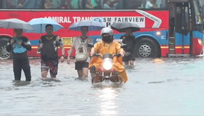 People swim, drive and wade through deep floodwater in Manila