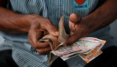 Rupee hits record low on month-end dollar demand; RBI helps cap losses
