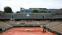 Spectators take shelter on Court Simonne Mathieu as rain swept across Roland Garros on Wednesday
