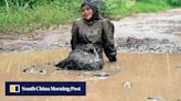 Indonesian mother who fell off bike sits in muddy potholes to decry bad roads