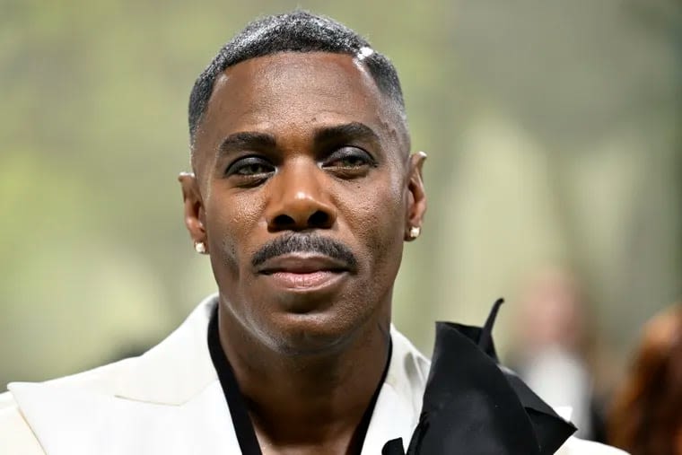 Colman Domingo arrives at the Met Gala red carpet in a dramatic white cape carrying a bouquet of lillies