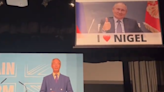 Nigel Farage speech interrupted by banner showing smirking Vladimir Putin