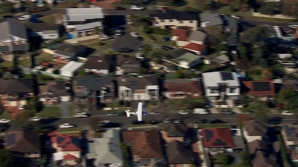 Small plane loses power and skims suburban rooftops before making safe crash landing on belly