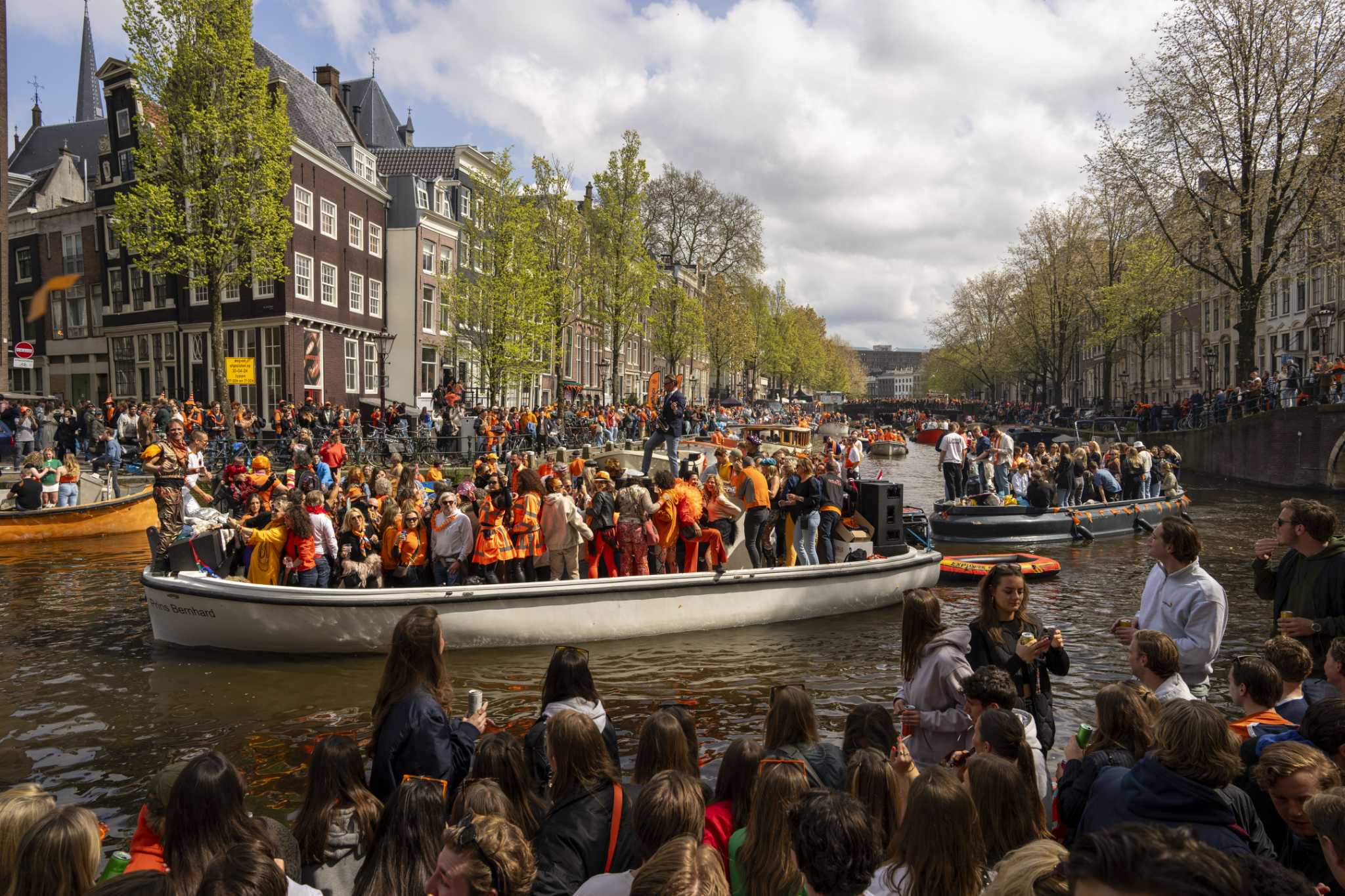 Orange crush: Boats packed with revelers tour Amsterdam canals to celebrate the king's birthday