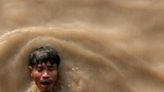 A man swims after a dive to recover a sunken ship in the Yangon River; scrap dealers buy the metal and melt it down to be used again