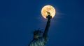 Flower Moon shines behind Statue of Liberty