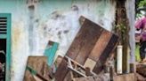 People clean a home that was damaged by mud and logs swept away by flash floods in western Indonesia